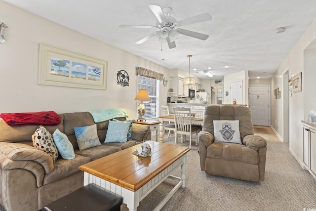 living area with light colored carpet, a ceiling fan, and baseboards