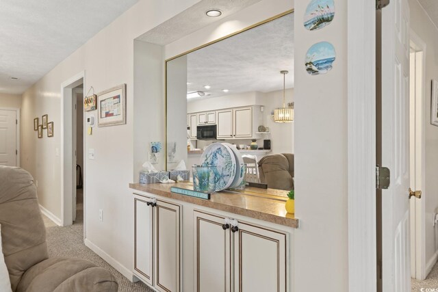 interior space featuring light colored carpet, a textured ceiling, decorative light fixtures, and a notable chandelier