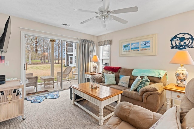 living room with a textured ceiling, carpet, and ceiling fan