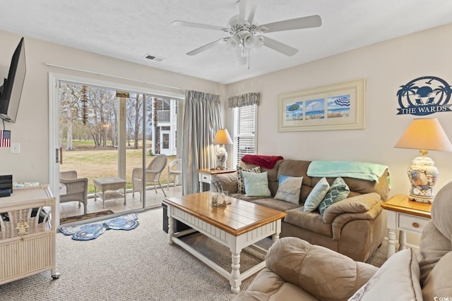 carpeted living area with ceiling fan, a textured ceiling, and visible vents