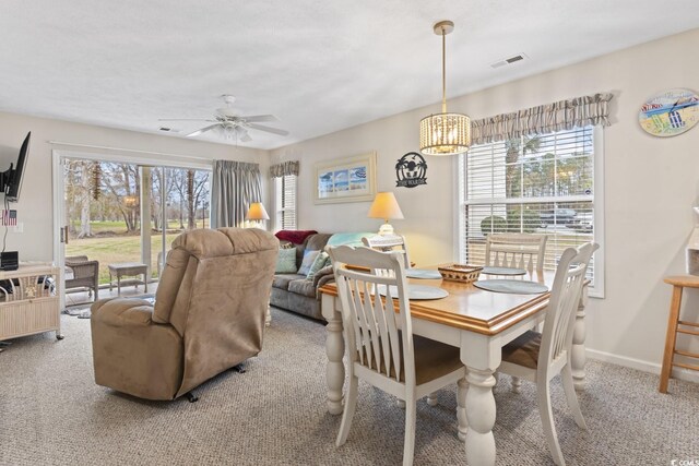 dining area featuring light carpet and ceiling fan with notable chandelier