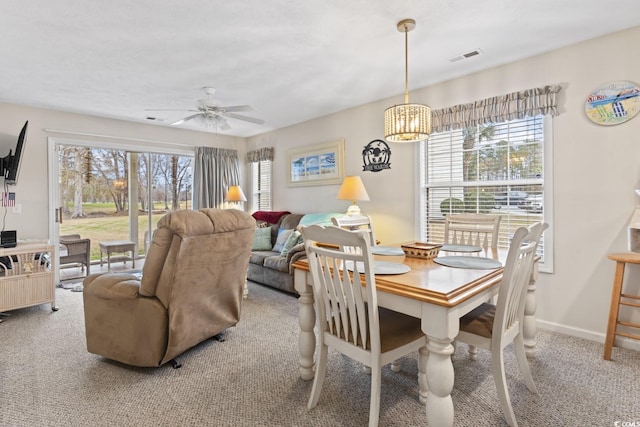 carpeted dining space featuring visible vents, baseboards, and ceiling fan