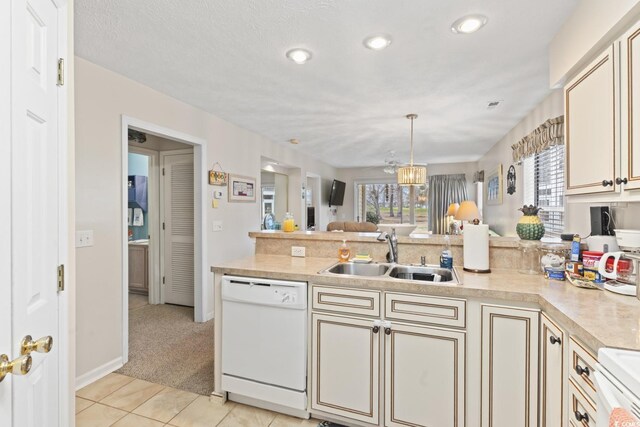 kitchen with pendant lighting, sink, light carpet, white appliances, and cream cabinets