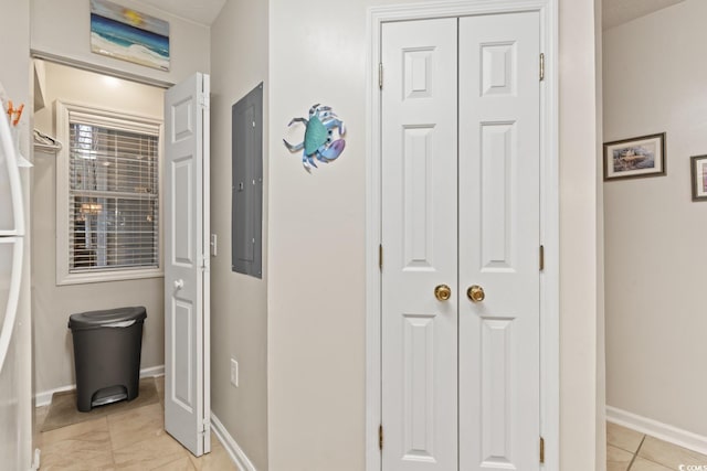 corridor with light tile patterned floors, electric panel, and baseboards