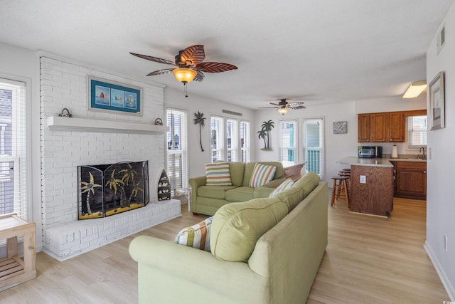 living room with a healthy amount of sunlight, a fireplace, and light hardwood / wood-style flooring