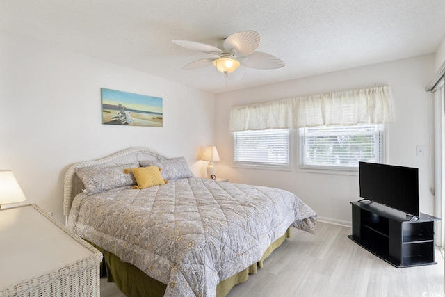 bedroom featuring light wood-type flooring, a textured ceiling, and ceiling fan