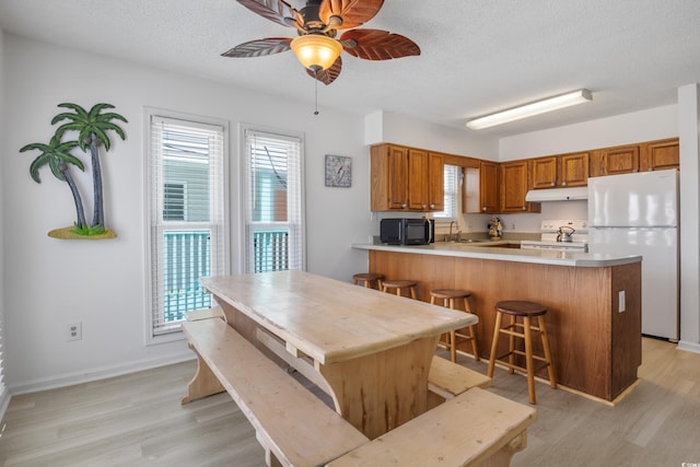 kitchen with light wood-type flooring, white appliances, ceiling fan, and kitchen peninsula