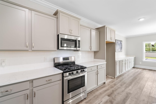 kitchen with appliances with stainless steel finishes, gray cabinetry, backsplash, light wood-type flooring, and ornamental molding