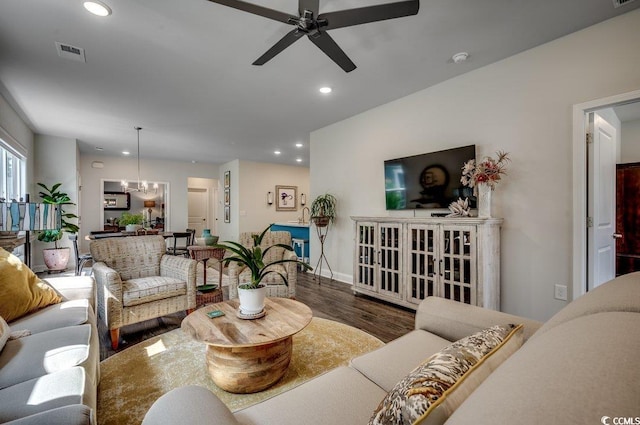 living room featuring ceiling fan with notable chandelier and dark hardwood / wood-style flooring