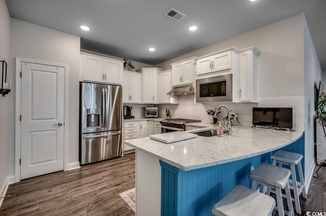 kitchen featuring kitchen peninsula, appliances with stainless steel finishes, dark wood-type flooring, sink, and white cabinetry