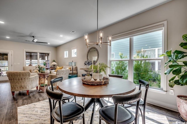 dining area featuring ceiling fan with notable chandelier and dark hardwood / wood-style flooring