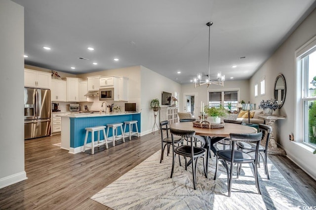 dining space with plenty of natural light, an inviting chandelier, and light wood-type flooring