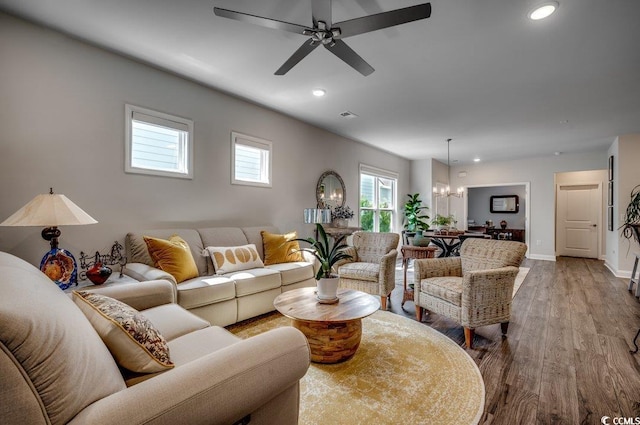 living room with ceiling fan with notable chandelier and light wood-type flooring