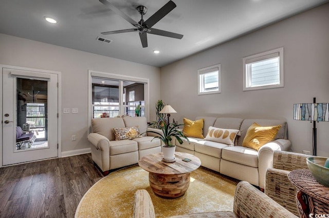 living room with dark wood-type flooring, ceiling fan, and a healthy amount of sunlight