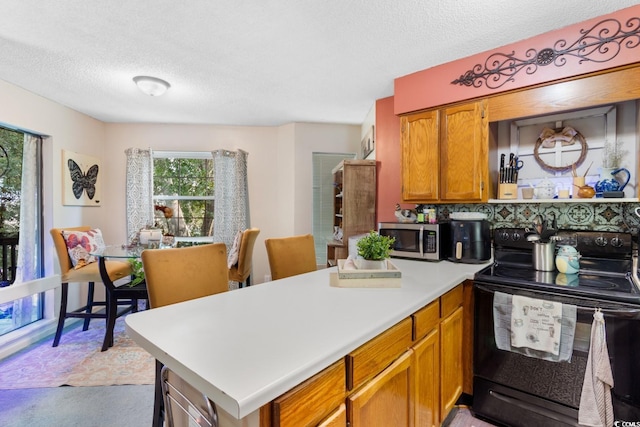 kitchen featuring kitchen peninsula, a textured ceiling, and black electric range