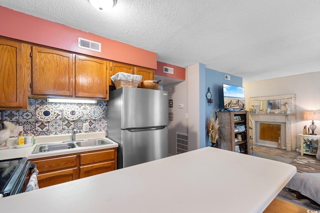 kitchen with a textured ceiling, stainless steel appliances, sink, and tasteful backsplash