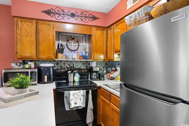 kitchen featuring a textured ceiling, appliances with stainless steel finishes, and backsplash