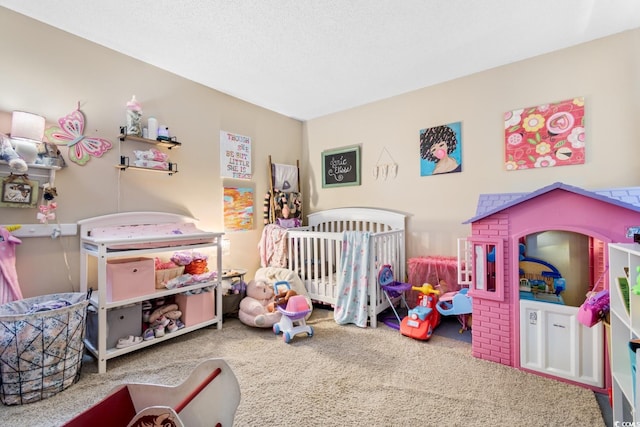 carpeted bedroom featuring a textured ceiling and a crib