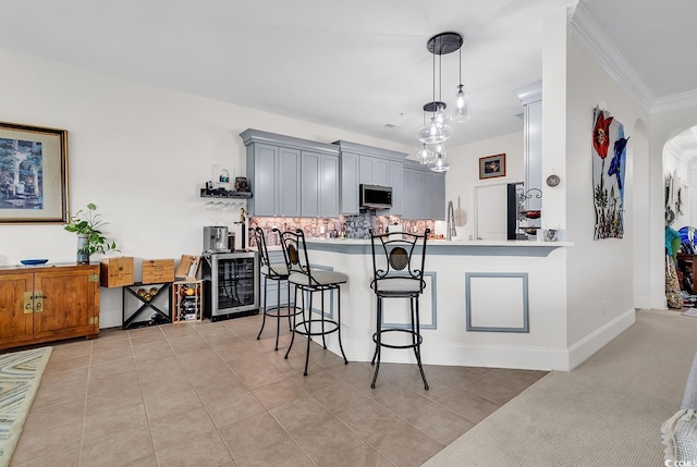 kitchen with stainless steel microwave, wine cooler, a breakfast bar area, light countertops, and arched walkways