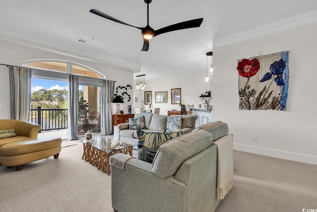 carpeted living room with visible vents, ceiling fan with notable chandelier, baseboards, and ornamental molding