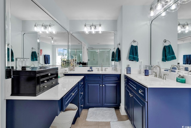 full bath with tile patterned flooring, two vanities, a stall shower, and a sink