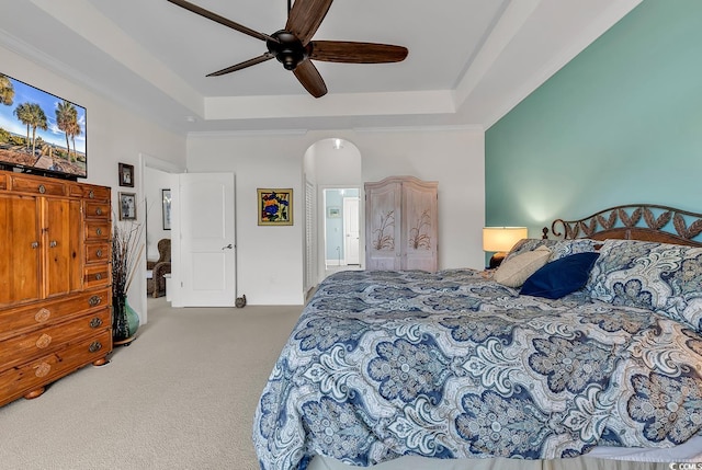 bedroom featuring arched walkways, a raised ceiling, a ceiling fan, and carpet floors