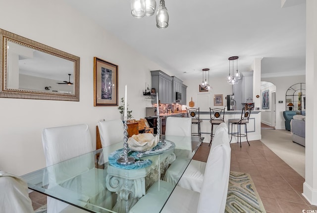 dining space featuring tile patterned floors, ceiling fan with notable chandelier, and arched walkways