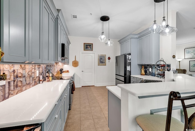 kitchen featuring visible vents, a kitchen bar, gray cabinetry, appliances with stainless steel finishes, and light countertops