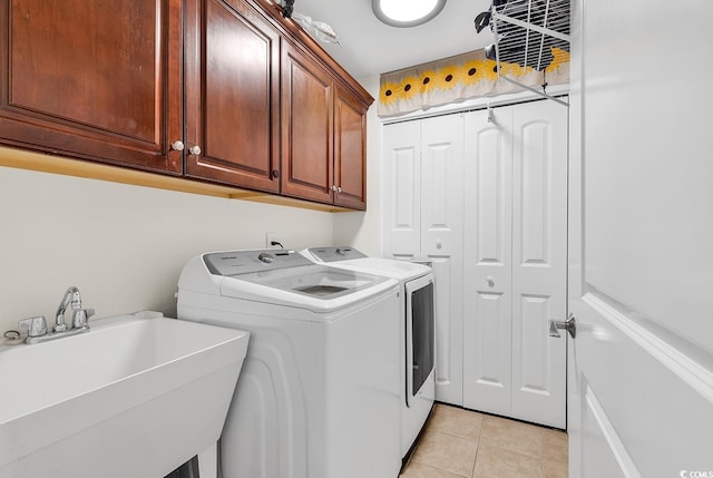 laundry room featuring cabinet space, light tile patterned floors, washer and dryer, and a sink