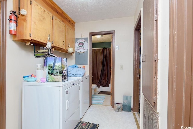 washroom featuring cabinets, washer and dryer, and a textured ceiling