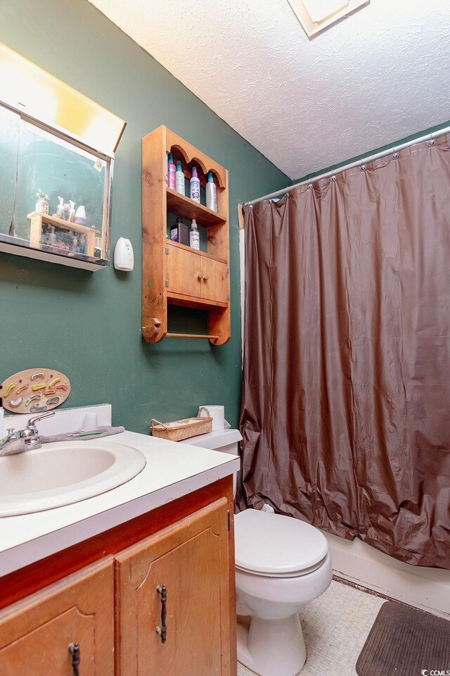 full bathroom featuring tile patterned flooring, a textured ceiling, shower / tub combo with curtain, vanity, and toilet