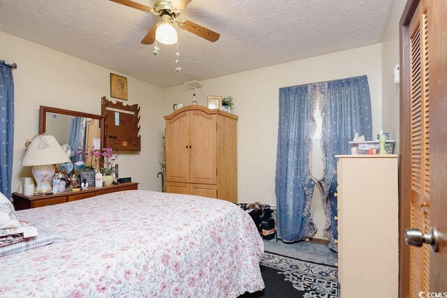 carpeted bedroom with ceiling fan, a textured ceiling, and a closet