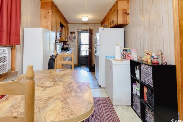 kitchen featuring white refrigerator, wood walls, and a textured ceiling