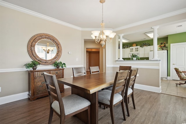 dining space featuring ornamental molding, an inviting chandelier, hardwood / wood-style flooring, and ornate columns