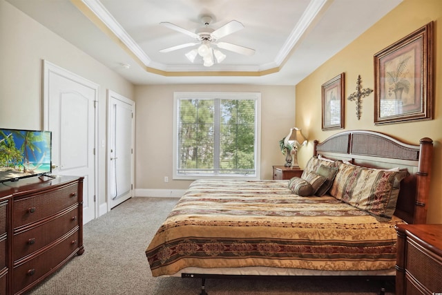 carpeted bedroom featuring a raised ceiling, ceiling fan, and ornamental molding