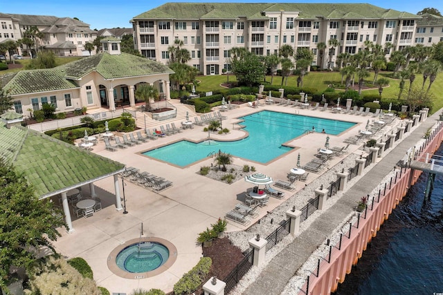 view of swimming pool with a gazebo, a patio area, a water view, and a hot tub