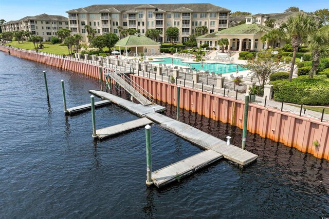 view of dock with a patio area, a community pool, and a water view