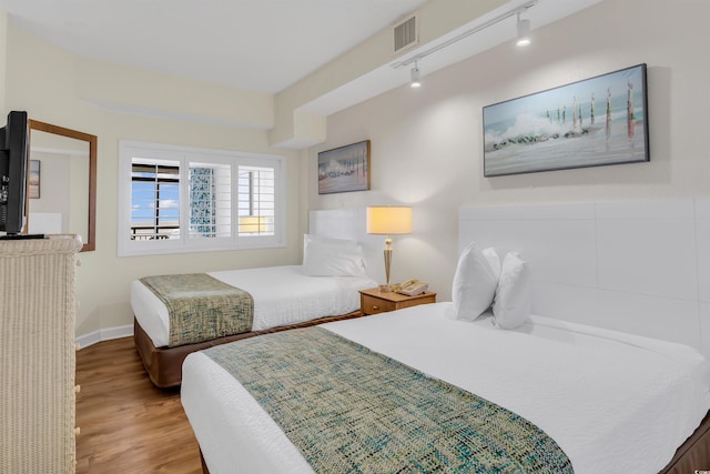 bedroom featuring rail lighting and light hardwood / wood-style floors