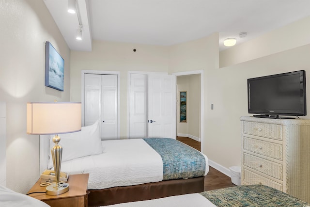 bedroom featuring dark wood-type flooring and rail lighting