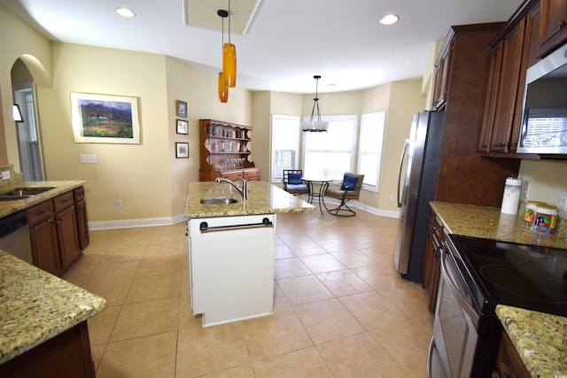 kitchen with light stone counters, decorative light fixtures, sink, and stainless steel appliances