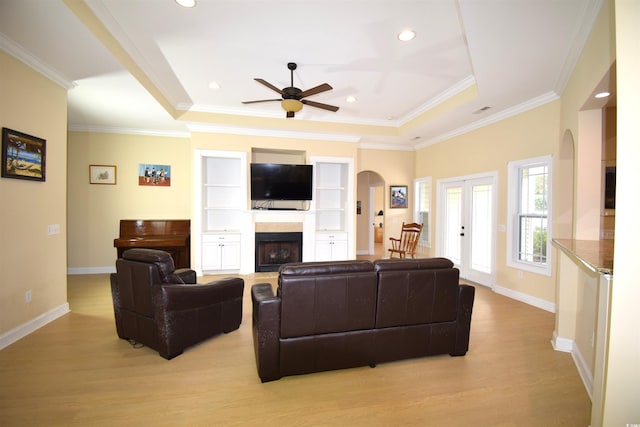 living room featuring light hardwood / wood-style flooring, a tray ceiling, ceiling fan, and ornamental molding