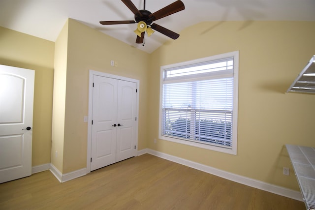 unfurnished bedroom featuring ceiling fan, a closet, light hardwood / wood-style flooring, and vaulted ceiling