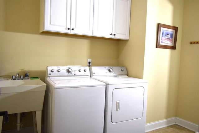 clothes washing area with light tile patterned floors, sink, washing machine and clothes dryer, and cabinets