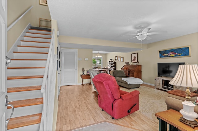 living room with ceiling fan with notable chandelier and light hardwood / wood-style flooring