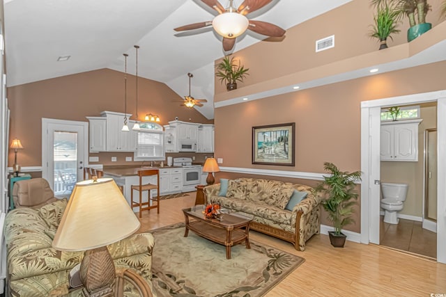 living room with high vaulted ceiling, light hardwood / wood-style floors, ceiling fan, and sink