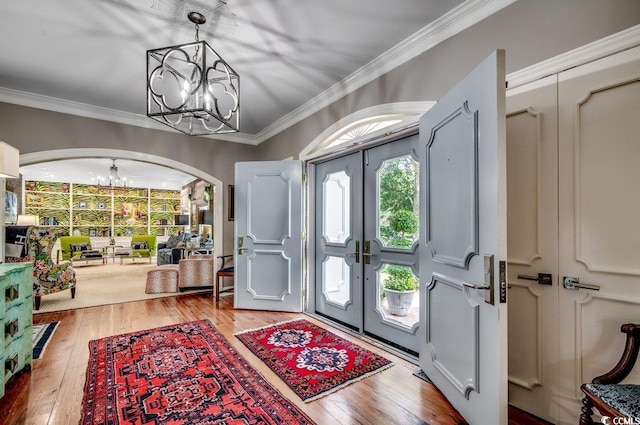 entrance foyer with crown molding, an inviting chandelier, hardwood / wood-style floors, and french doors