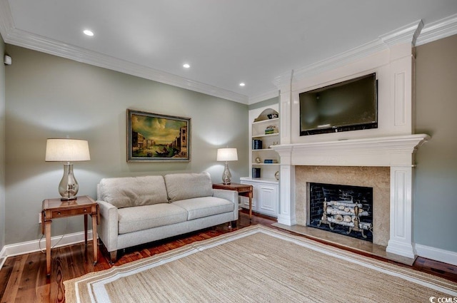 living room featuring crown molding, a premium fireplace, wood-type flooring, and built in features