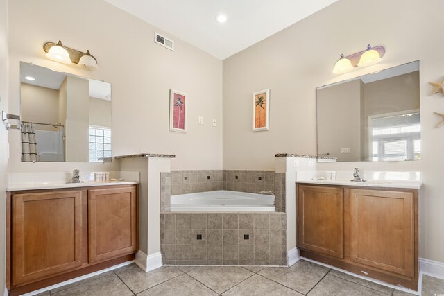 bathroom featuring tiled tub, vanity, and tile patterned flooring