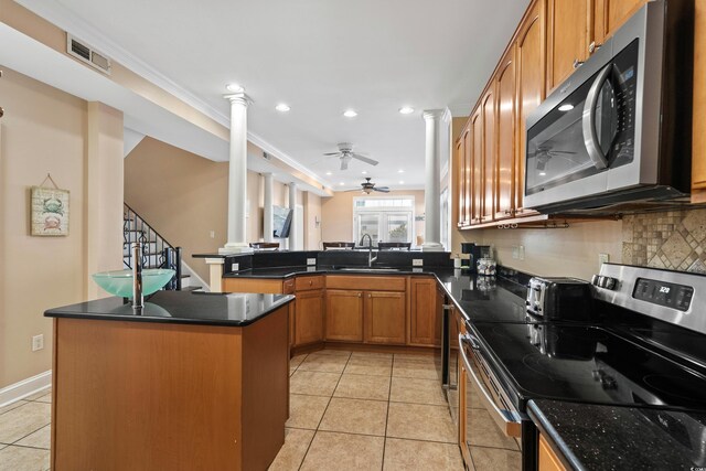 kitchen featuring light tile patterned flooring, appliances with stainless steel finishes, decorative columns, sink, and kitchen peninsula