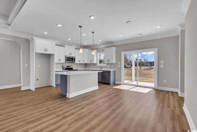 kitchen featuring ornamental molding, white cabinetry, stainless steel appliances, arched walkways, and light countertops